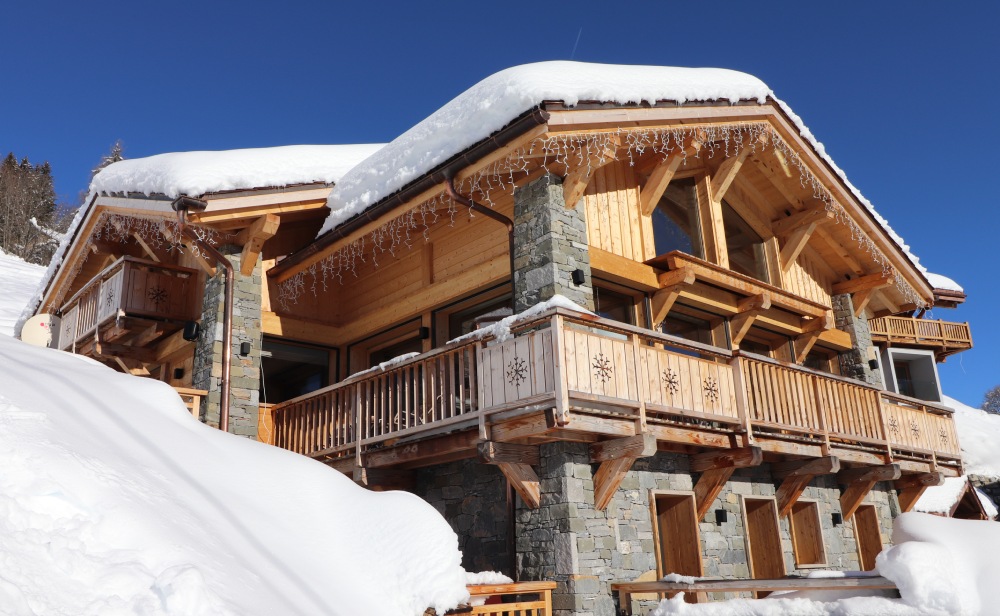 Imposant chalet de montagne sous la neige, pierres et bois, construction sur mesure