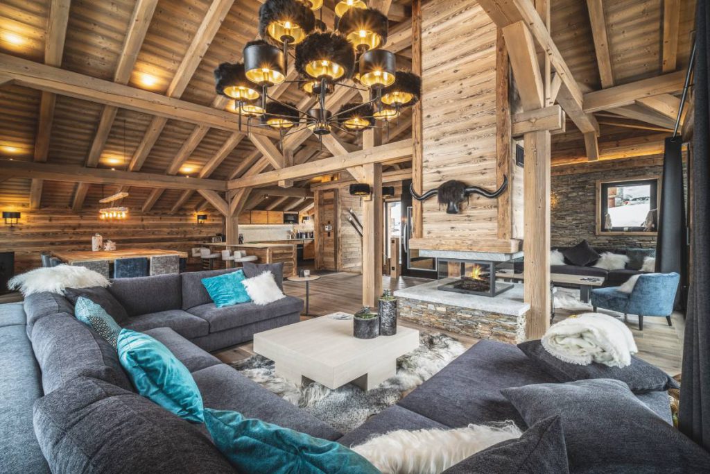 Grand séjour sous charpente, belle hauteur sous plafond, jeu d'éclairage qui met en valeur la structure bois du chalet. Chalet bois sur mesure entre traditionnel et contemporain.