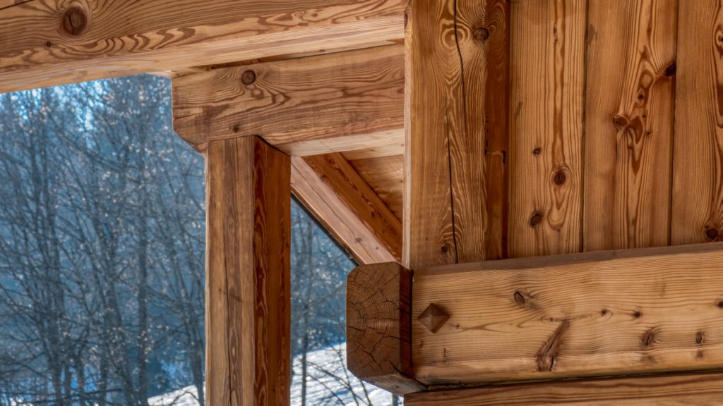 Gros plan sur un assemblage de charpente bois traditionnelle, chalet poteau poutre en mélèze.